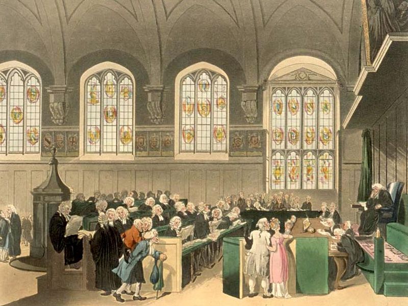 Engraved illustration of the court of Chancery at Lincoln's Inn, sometime around the year 1800. The room has a high, vaulted ceiling, with a row of tall, stained-glass windows along the back wall. Rows of lawyers are seated, wearing black gowns and white wigs; facing them is a seated judge on a raised stand, leaning on one elbow. A number of clerks are sitting in front of the judge at ground level, taking down notes. One lawyer is standing, addressing the judge, while in the foreground a few more are talking. In the foreground, a stooped old man in a blue coat is walking in, while a man and a woman are standing with linked arms looking anxiously at the judge: he is wearing a powdered wig, a white coat and breeches, while she wears a white petticoat with a pink gown over it. All the faces are drawn in a slightly comical style, a bit like caricatures.